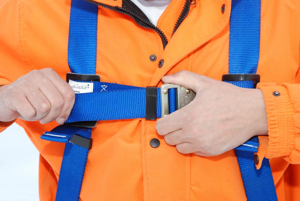 Close up of worker tightening fall protection harness